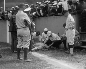 Ruth falls up against the concrete wall trying to field a fly ball. He was out for five minutes as the team trainer works on him.